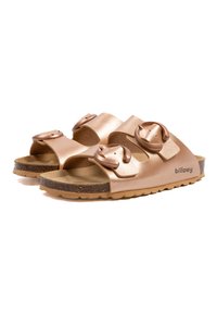 Sandales à glisser en or rose avec deux sangles à boucle réglables, semelle en liège, semelle en caoutchouc texturée et une marque "billowy" sur le côté.