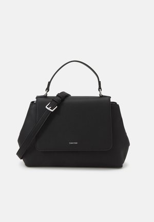 Sac à main noir structuré avec une poignée supérieure et une bandoulière réglable, doté d'un rabat à l'avant et d'un petit logo Calvin Klein.