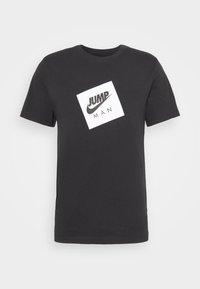 Černé bavlněné tričko s bílým čtvercovým grafickým designem, pod nímž je text "JUMP" a "MAN", klasický kulatý výstřih a krátké rukávy.
