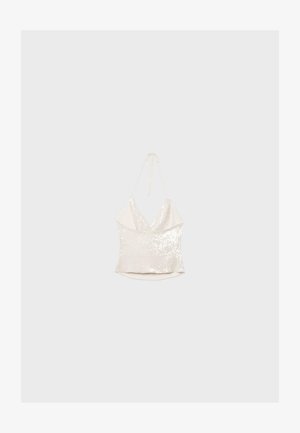 Hvid paliet halterneck top med dybt V-udskæring og bindebånd bagpå, vist mod en ensformet lysegrå baggrund.