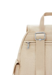 Zaino in tessuto beige di forma rettangolare, con una tasca frontale con zip e una spallina robusta con un accento metallico.