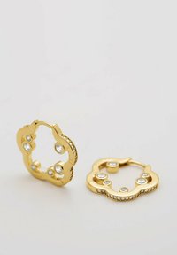 Goldfarbene Creolen mit gewelltem Design, fünf eingelassenen klaren Kristallen und einer strukturierten Kante mit Steinen entlang der Basis.