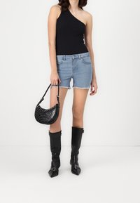 Černý top s jedním ramenem, denimové kraťasy s roztrhaným lemem, černá kabelka se špičatými hroty a černé kozačky nad kolena se špičatými špičkami a s přezkami.