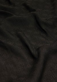 Sort tekstil med et subtilt mønster, blød tekstur og draperet udseende, der viser indviklet detaljer i en glat, elegant finish.