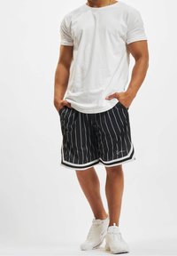 Černobílé pruhované sportovní šortky s bílým lemem, spárované s jednoduchým bílým tričkem a bílými teniskami. Pohodlný střih, šortky do délky kolen.
