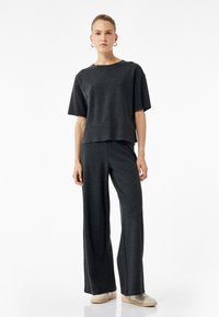 Mørkegrå, afslappet-fittet top med korte ærmer parret med vide bukser i matchende stof, der har en blød tekstur og minimalistisk design.