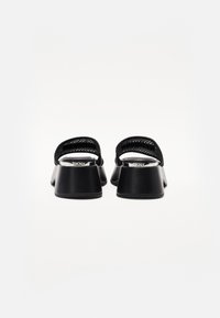 Black sandals with a rounded toe, mesh strap, and chunky heel. Features a smooth texture with a glossy finish on the insole.
