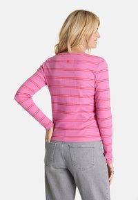 Langärmliges pinkes Oberteil mit roten Streifen, weicher gerippter Textur, mit einem kleinen Knopfdetail auf der Rückseite und klassischem Rundhalsausschnitt.