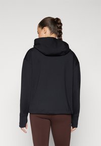 Black hooded sweatshirt made of soft fabric, featuring a relaxed fit, drop shoulders, and thumbholes at the cuffs. Smooth texture.