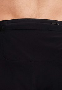 Shorts de bain noirs avec une texture lisse, une taille élastique et une poche zippée à l'arrière pour le rangement.