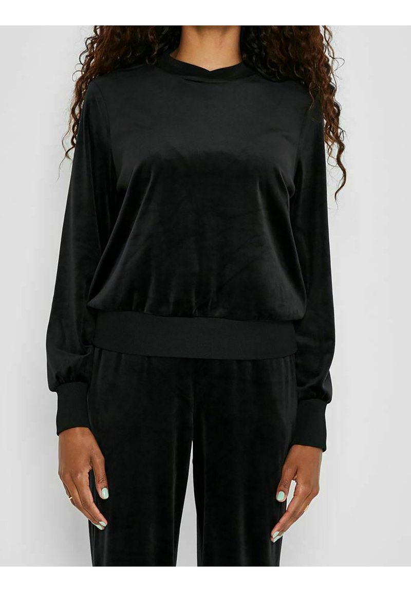 Top lungo in velluto nero con maniche lunghe e scollo rotondo, caratterizzato da una texture liscia e polsini elasticizzati, abbinato a pantaloni neri coordinati.