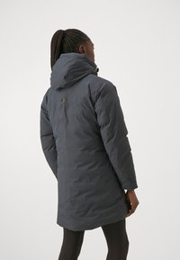Tmavě šedá zateplená parka s kapucí, má decentní logo na zadní straně, hladkou texturu, středně dlouhý design a žádné viditelné zapínání.