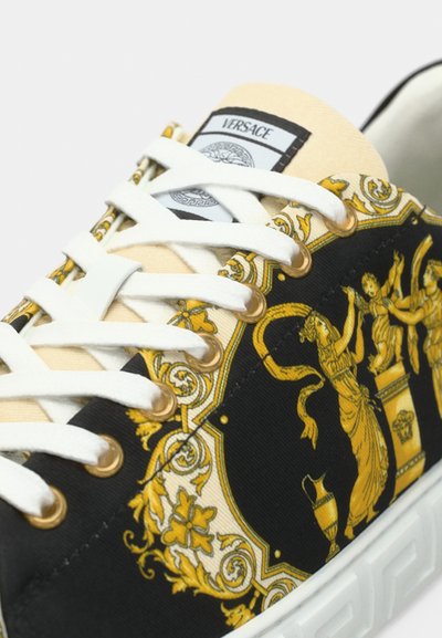 Versace sportiniai bateliai su juodu audinio viršumi, papuošti auksinėmis ir kreminėmis baroko raštais, baltais raišteliais ir tekstūruotu guminiu padu.