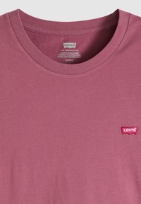 Κοντομάνικο T-shirt με στρογγυλή λαιμόκοψη από βαμβακερό ύφασμα σε απόχρωση ξεθωριασμένου ροζ, με ένα μικρό κόκκινο λογότυπο Levi's στο αριστερό μέρος του στήθους.