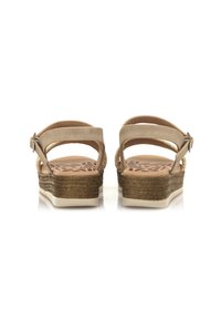 Sandalias beige con tira al tobillo y un tacón de cuña texturizado, que cuentan con un diseño trenzado y una plantilla acolchada con un patrón de hojas.