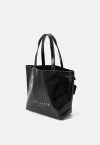 Musta kiiltohohtoinen olkalaukku, jossa on kaksoiskahvat ja etuosassa kultainen logo "TED BAKER LONDON". Laukku on rakenteellisesti muotoiltu ja siinä on kiiltävä pinta.