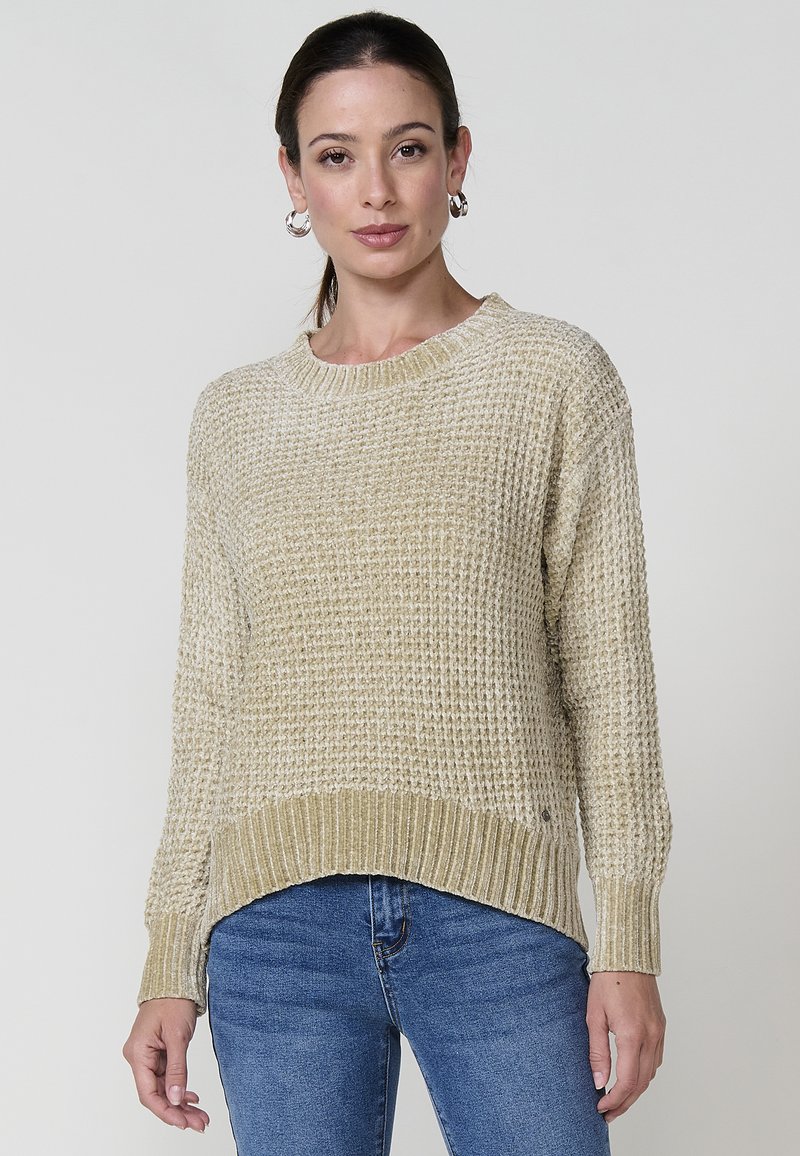 Kootud sviiter heledas beežis, millel on tekstuuriline muster, ümmargune kaelus ja soonik äär. Omab pikki varrukaid ja lõdva lõikega.