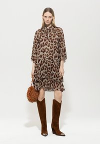 Leopardenmuster Chiffonkleid mit hohem Kragen und Rüschenschichten, kombiniert mit braunen Wildlederstiefeln bis zum Knie und einer strukturierten braunen Handtasche.