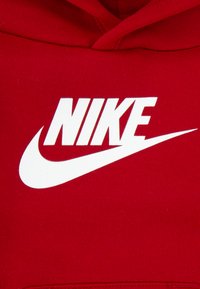 Hanorac roșu din bumbac cu un logo mare alb „NIKE” și design swoosh pe partea din față. Textură netedă și croială clasică.