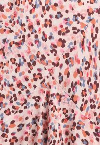 Mustriline kangas, millel on hele roosa taust ja väikesed, ebaregulaarse kujuga täpid pruunis, oranžis ja sinises. Pehme tekstuur, langev disain.