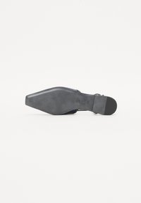 Chaussure à talon aiguille avec un bout pointu, en matériau bleu marine, finition brillante, semelle texturée noire et détail de sangle métallique.