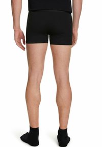 Czarne bokserki o dopasowanym kroju, wykonane z miękkiej tkaniny bawełnianej, z elastycznym paskiem w talii. Model pokazany z tyłu.