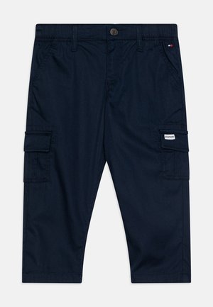 Calças de carga azul-marinho com fecho de botão, cintura elástica, múltiplos bolsos laterais e detalhes de costura. Tecido liso sem padrões.