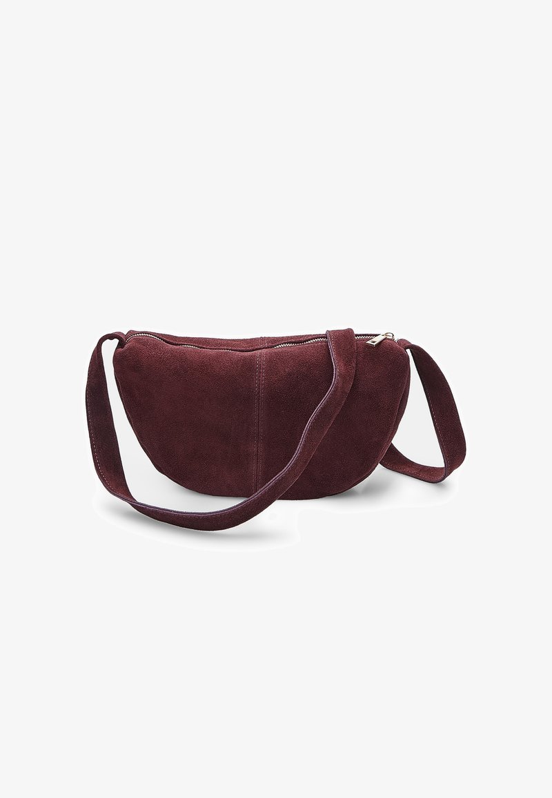 Borsa a tracolla in suede bordeaux con forma curva, chiusura con zip e tracolla regolabile, caratterizzata da una texture morbida e un design minimal.