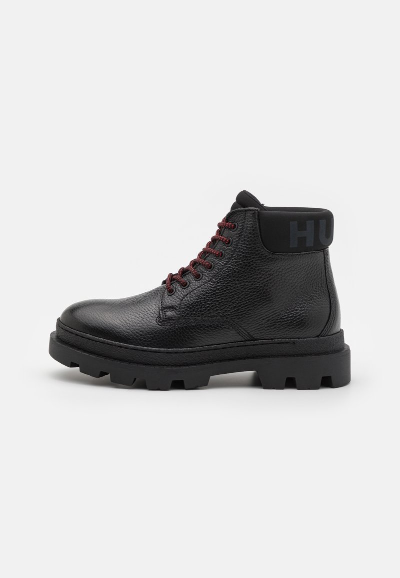 Schwarze Leder-Ankle-Boots mit einer strukturierten Oberfläche, roten Schnürsenkeln und einem gepolsterten schwarzen Kragen mit "HU" in Blau. Dicke Gummisohle mit Profil.