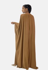 Braunes, langärmliges, fließendes Kleid aus weichem Stoff mit rundem Ausschnitt und dezenten Drapierungen. Mit einem Schlitzdetail am Rücken.