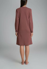Abito a maniche lunghe, lungo fino al ginocchio, in tessuto bordeaux con motivo geometrico, con dettagli in bottone sulle maniche e silhouette dritta.