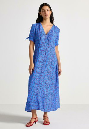 Blå blommig maxiklänning med korta ärmar, v-ringning, knappar framtill och röda accenter. Tyget har ett lätt och texturerat utseende.