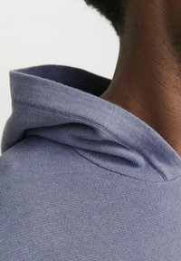 Hellblauer Kapuzenpullover aus einem strukturierten Stoff, mit einer eng anliegenden Kapuze und einem glatten, weichen Halsausschnitt.