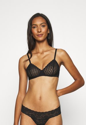 Svart blonde BH med geometrisk mønster, justerbare stropper og bølgete kanter. Kombinert med matchende blonde truse. Glatt stofffinish.