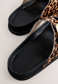 Scarpe slip-on con stampa leopardata, suole in gomma nera, interno liscio nero e dettagli in metallo color oro. Tomaia in tessuto morbido per il massimo comfort.