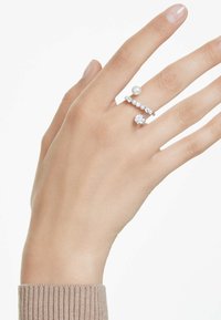 Drei Ringe an einer Hand: einer mit einem großen klaren Stein, einer mit kleinen klaren Steinen und einer mit einer runden Perle, alle im Silberton.