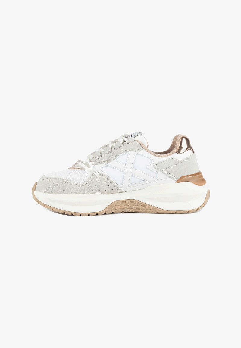 Baskets blanches et gris clair avec semelle beige et détails métalliques bronze, vue de profil sur fond blanc.