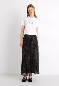 Weißes T-Shirt mit "Dream" Stickerei, kombiniert mit einem langen, schwarzen Tüllrock mit dezentem Leopardenmuster. Schwarze Schuhe runden das Outfit ab.