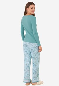Turquoise lange mouwtop gecombineerd met lichtblauwe gestreepte pyjamabroek met bloemenpatronen en contrasterende afwerking bij de manchetten. Zacht materiaal.