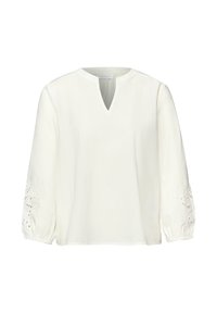 Blouse blanche à manches longues avec encolure en V à fente et poignets élastiques, ornée de détails en dentelle florale ajourée sur les manches.