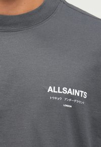 Σκούρο γκρι κοντομάνικο μπλουζάκι από βαμβάκι με στρογγυλή λαιμόκοψη και λευκό τυπωμένο κείμενο: "ALLSAINTS," ιαπωνικούς χαρακτήρες και "LONDON."