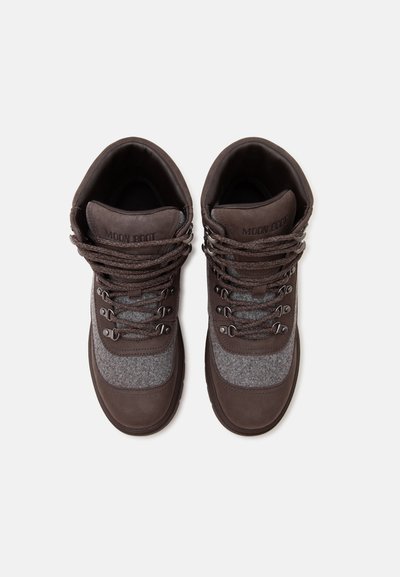 Paire de chaussures de randonnée Moon Boot marron et grises avec des lacets épais et des colliers rembourrés autour de la cheville, vues de dessus sur un fond blanc.