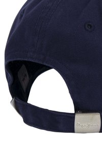 Gorra azul navy hecha de algodón con una superficie texturizada, que presenta una hebilla de metal plateada con marca en relieve y una correa ajustable en la parte posterior.