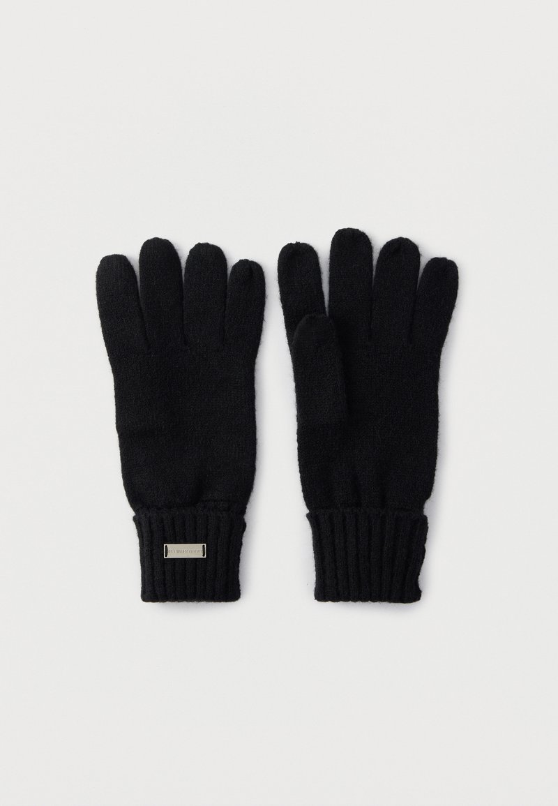 Para czarnych rękawiczek dzianinowych z prążkowanymi mankietami oraz małą prostokątną metalową plakietką na jednym nadgarstku, ułożonych płasko na białym tle.