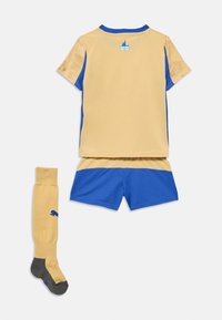 Žltý a modrý športový komplet obsahuje tričko s krátkym rukávom, šortky a podkolienky s logom. Materiál má hladkú štruktúru.