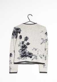 Pull en laine gris à motif floral gris foncé. Texture douce, manches longues, encolure arrondie, et finition noire au niveau de l'ourlet et des poignets. Accroché sur un crochet.