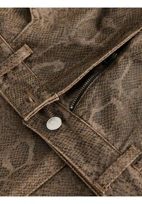 Rjavi umetni usnjeni material s vzorcem kačje kože, z vidnim zadrgo, kovinskim gumbom in strukturiranimi šivi. Teksturirana površina.