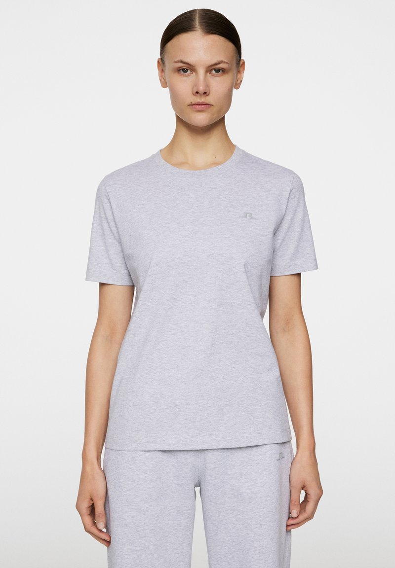 Jasnoszara bawełniana koszulka z okrągłym dekoltem i krótkimi rękawami. Posiada subtelny detal logo na piersi oraz luźny krój.