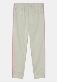 Calças de treino cinzentas claras com uma cintura elástica, apresentando riscas laterais brilhantes em rosa e punhos elásticos nos tornozelos.