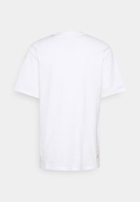 Bílý bavlněný tričko s kulatým výstřihem a krátkými rukávy. Má rovný lem a malou logovou aplikaci blízko lemu na levé straně.